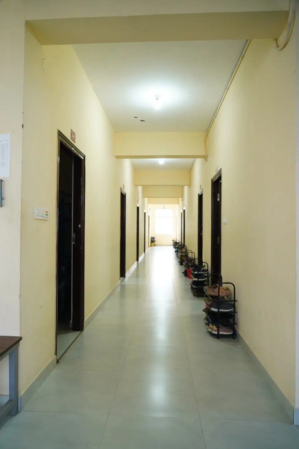 A hostel corridor with shoe racks outside the rooms